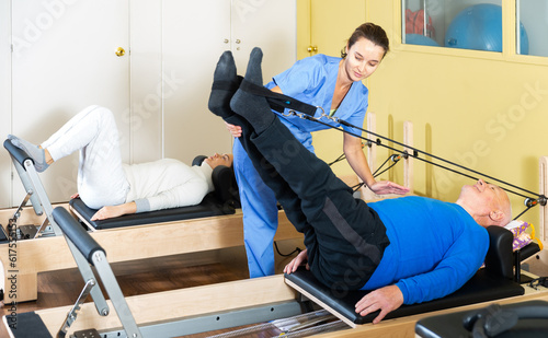 Senior man workout in rehabilitation center. Personal trainer helping senior man