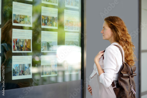 Bild auf Leinwand Young pregnant woman exploring storefront of real estate agency