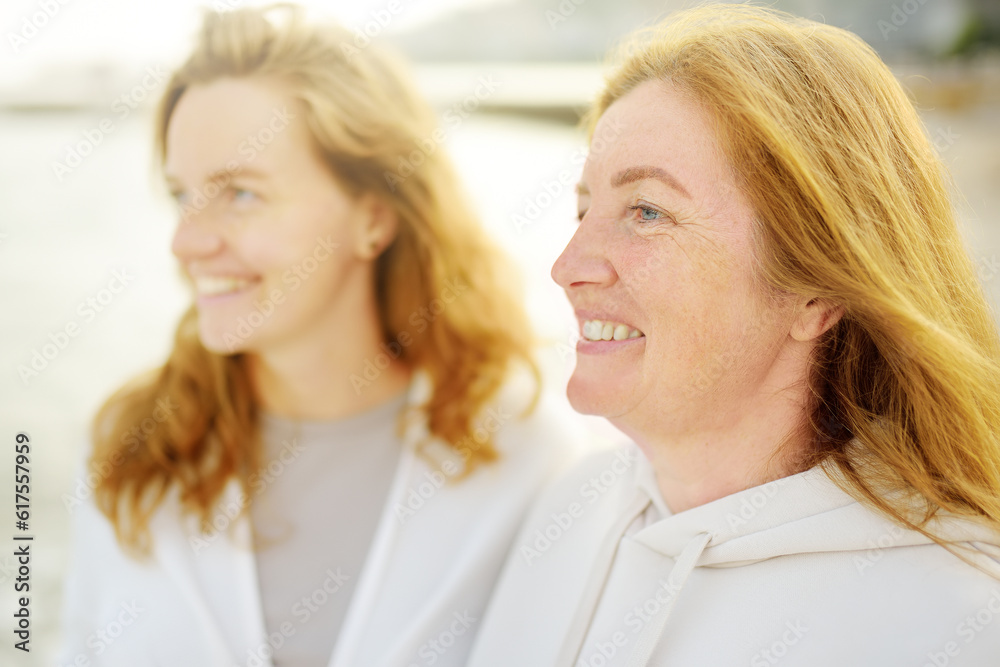 Redhead senior mother and her beautiful adult daughter are walking together and laughing Redhead senior mother and her beautiful adult daughter are walking together and laughing