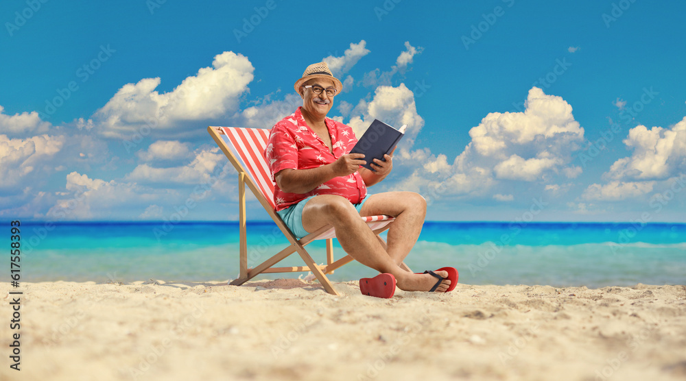 Male tourist with a book sitting in a bech chair by the sea