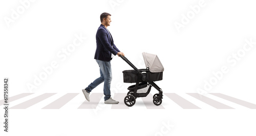 Full length profile shot of a father with a pushchair walking at a pedestrian crossing