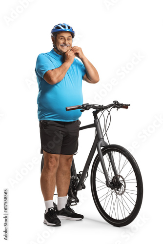 Fototapeta Naklejka Na Ścianę i Meble -  Mature man with a bicycle putting on a helmet