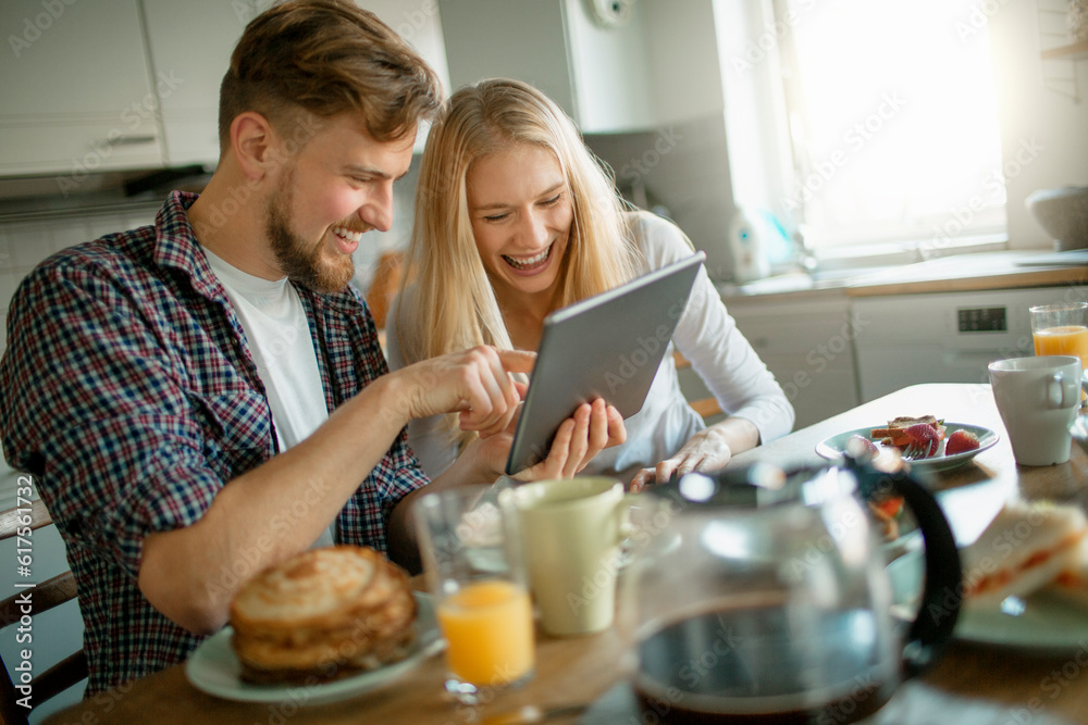 Young couple using a digital tablet while having breakfast in the morning