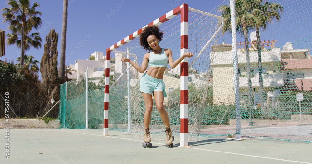 Φωτογραφία Young fit female in summer outfit and roller skates standing near football gates and laughing on playground