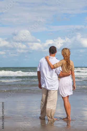 Rear view of romantic young man and woman couple embracing on a beach