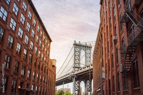 Fototapeta Naklejka Na Ścianę i Meble -  Manhattan Bridge between Manhattan and Brooklyn over East River seen from a narrow alley enclosed by two brick buildings on a sunny day, New York City