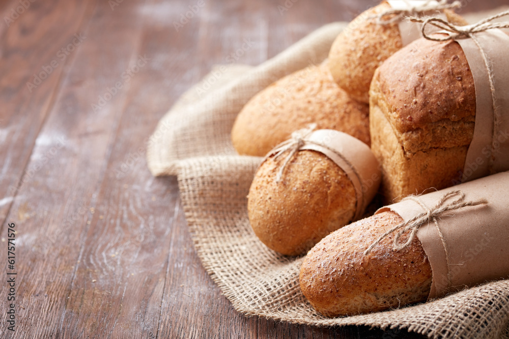 Fresh hot bread in a linen towel on a brown wooden table. free space for writing text. menu. advertising. Bakering. Food and pastries. Bakery. Fresh hot bread in a linen towel on a brown wooden table. free space for writing text. menu. advertising. Bakering. Food and pastries. Bakery.