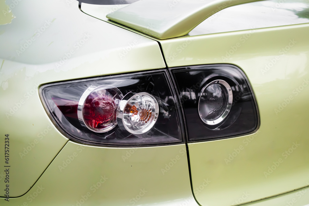 Close-up glossy tail light of car with leaf green paint.