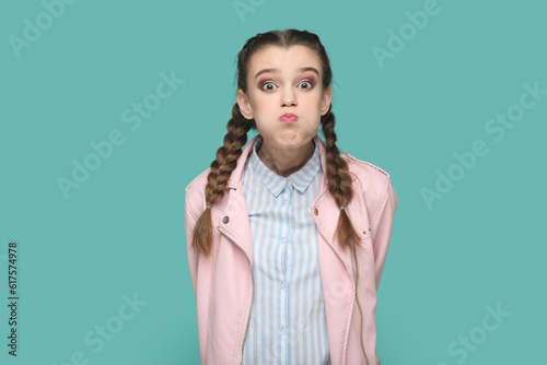 Fényképezés Portrait of funny teenager girl with braids wearing pink jacket blowing cheeks and puffing breath, has attractive look keeps silence with friends