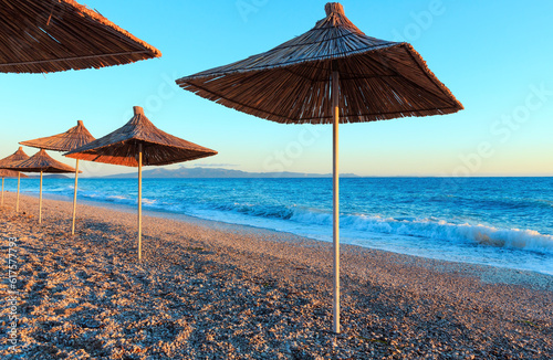Summer sunset beach with strawy sunshades (Albania). photo