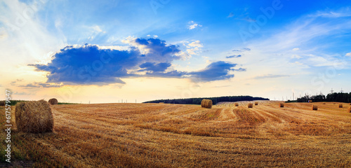 Hay bales on field. Rural landscape with haystacks. Autumn field with hay bales after harvest. Rural landscape with haystacks against the backdrop of a beautiful sunset sky