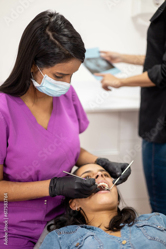 dental equipment and healthcare professional lifestyle at workplace  woman wearing protections  dentist performing oral treatment to patient