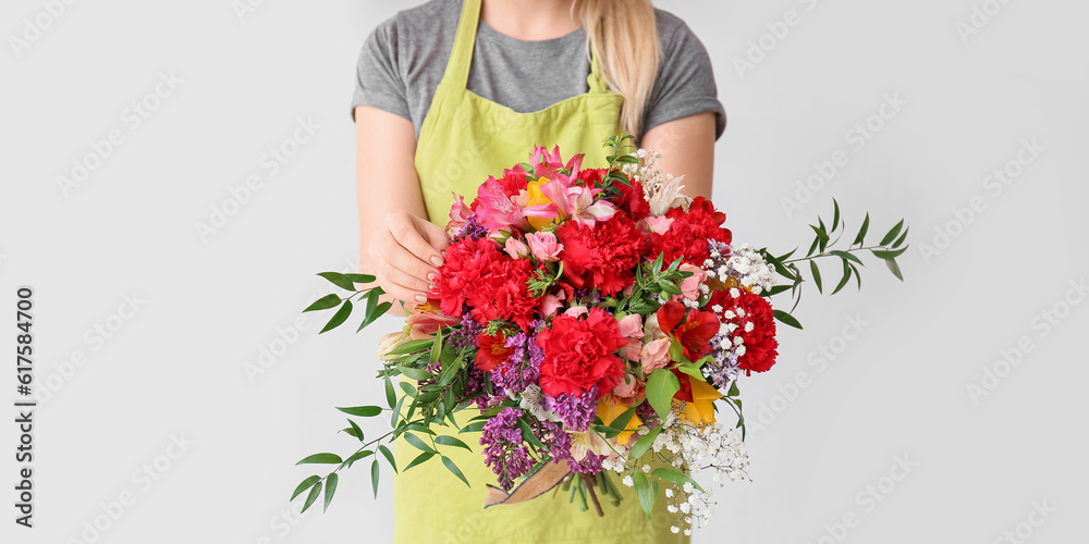 Female florist with beautiful bouquet on light background, closeup