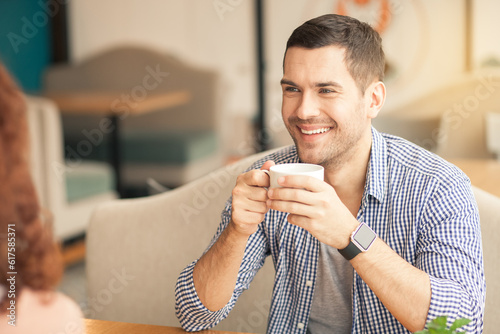 Date in cafe. Lovely couple in cafe with stylish interior. Man smiling and looking at woman. They having cups of coffee