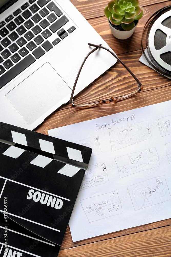 Fototapeta premium Storyboard with movie clapper, laptop and eyeglasses on wooden background