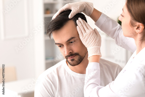 Fotomurale Doctor examining young man's hair in clinic, closeup