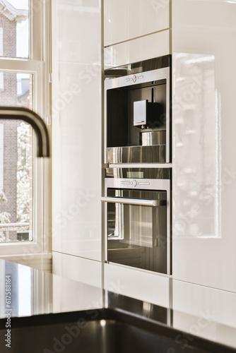 a white kitchen with black counter tops and an oven on the wall in the center of the photo is a large window