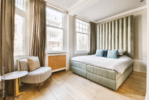 a bedroom with a bed, chair and window overlooking the cityscapearn com logo on the wall