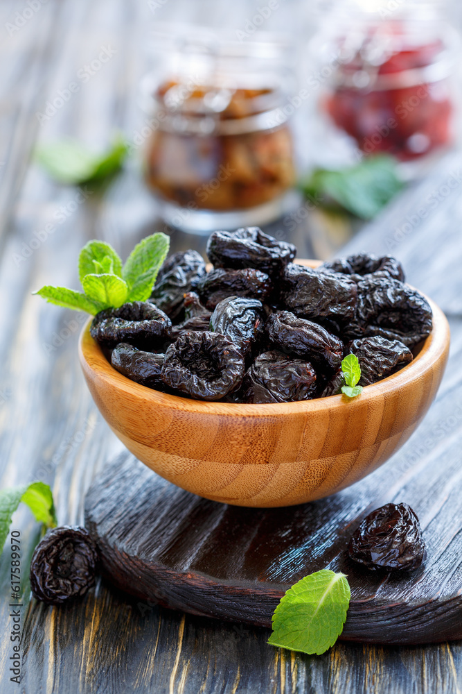 Dried prunes in a bowl on wooden table, selective focus. Dried prunes in a bowl on wooden table, selective focus.