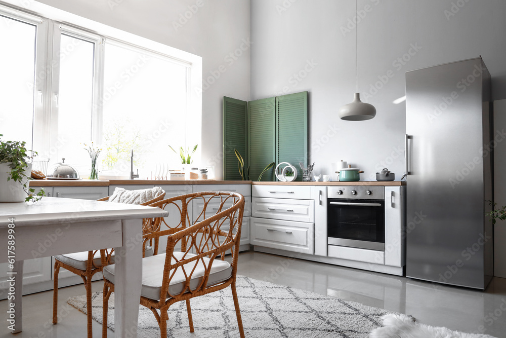 Interior of light kitchen with stylish fridge, counters, table and ...