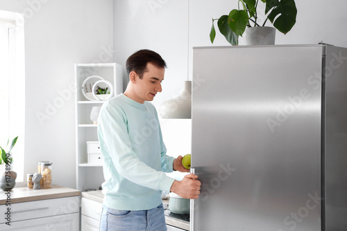 Canvastavla Handsome man opening fridge in kitchen