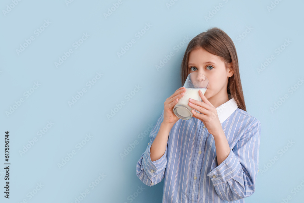 Little girl drinking milk on light blue background Little girl drinking milk on light blue background