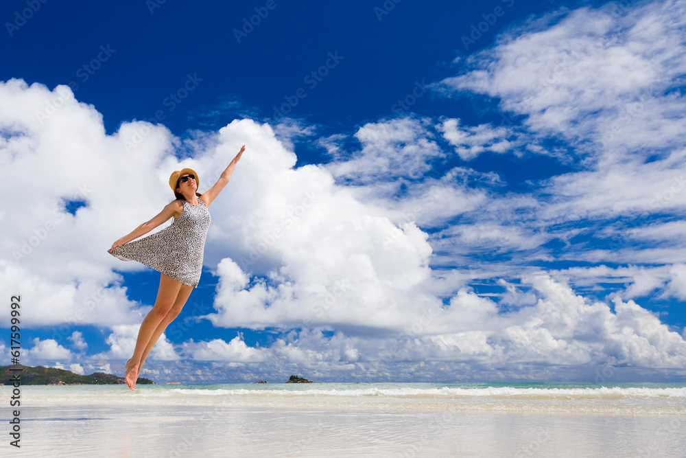 Beautiful woman jumping on the wonderful beach of Praslin, Seychelles Beautiful woman jumping on the wonderful beach of Praslin, Seychelles