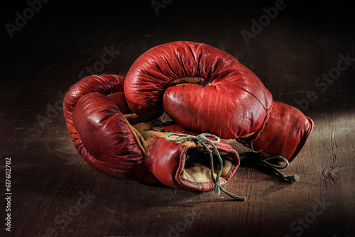 Old red boxing gloves on wooden background. © Designpics