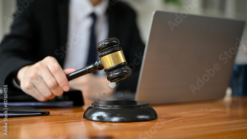 Close-up image of a professional male lawyer holding a judge gavel at his desk