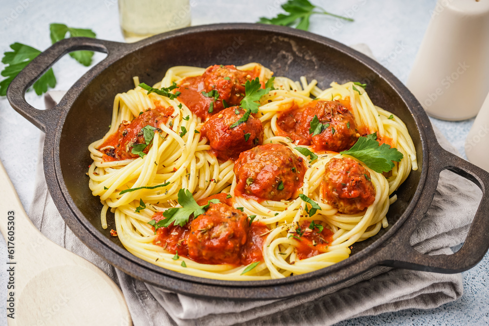 Frying pan of boiled pasta with tomato sauce and meat balls on white table Frying pan of boiled pasta with tomato sauce and meat balls on white table