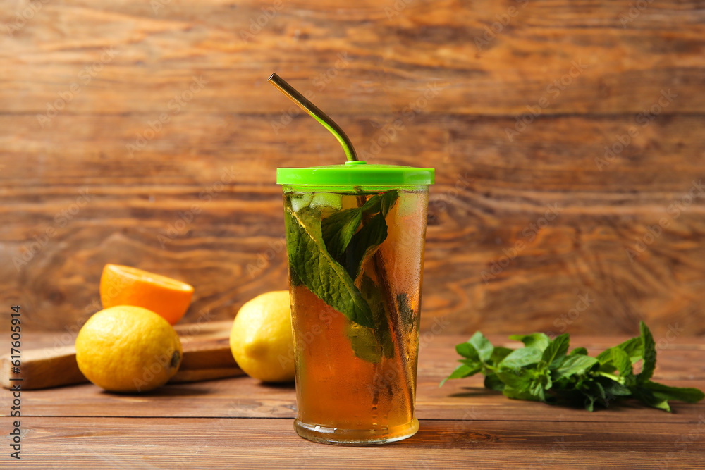 Fototapeta premium Glass of ice tea with mint and lemon on wooden background