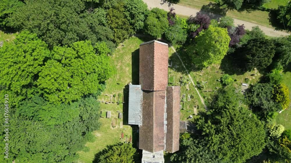 An orange tiled rooftop of a church surrounded by lush green trees in the village of Littlebourne, Kent, England