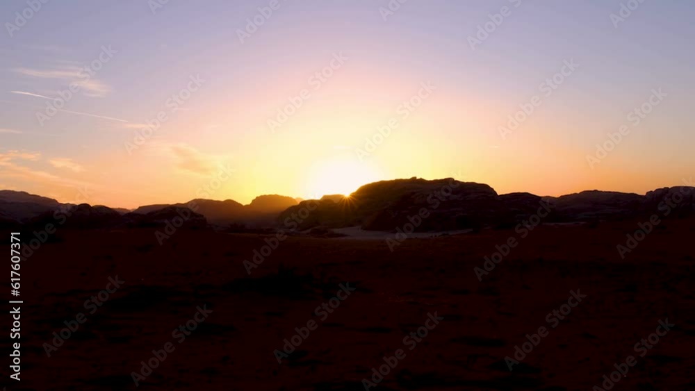 Sunset and last rays of sunlight disappearing behind mountains in remote wilderness of Wadi Rum desert in Jordan Sunset and last rays of sunlight disappearing behind mountains in remote wilderness of Wadi Rum desert in Jordan