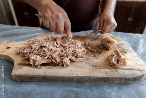 An adult Hispanic woman is chopping beef on a kitchen table