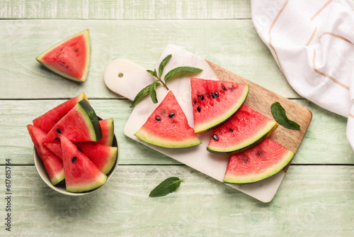 Board and bowl with pieces of fresh watermelon on green wooden background