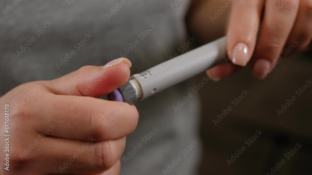 Close-up of an unrecognizable diabetic woman dialing the correct dose of insulin on a syringe pen before an injection. The concept of medicine and treatment of type 1 diabetes.