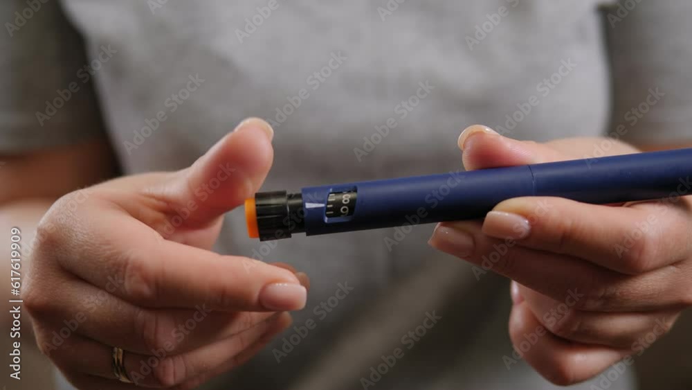 Close-up of a diabetic woman dialing the right dose of prolonged insulin on a syringe pen at home. Treatment for type 1 diabetes. Close-up of a diabetic woman dialing the right dose of prolonged insulin on a syringe pen at home. Treatment for type 1 diabetes.