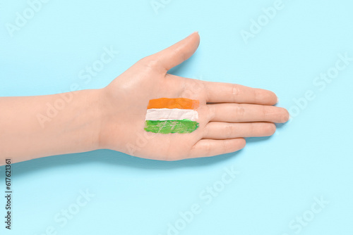 Female hand with drawn flag of India on blue background