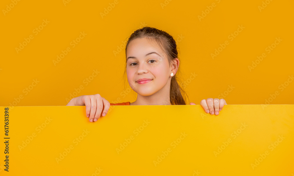cheerful girl behind blank yellow paper with copy space for advertisement cheerful girl behind blank yellow paper with copy space for advertisement