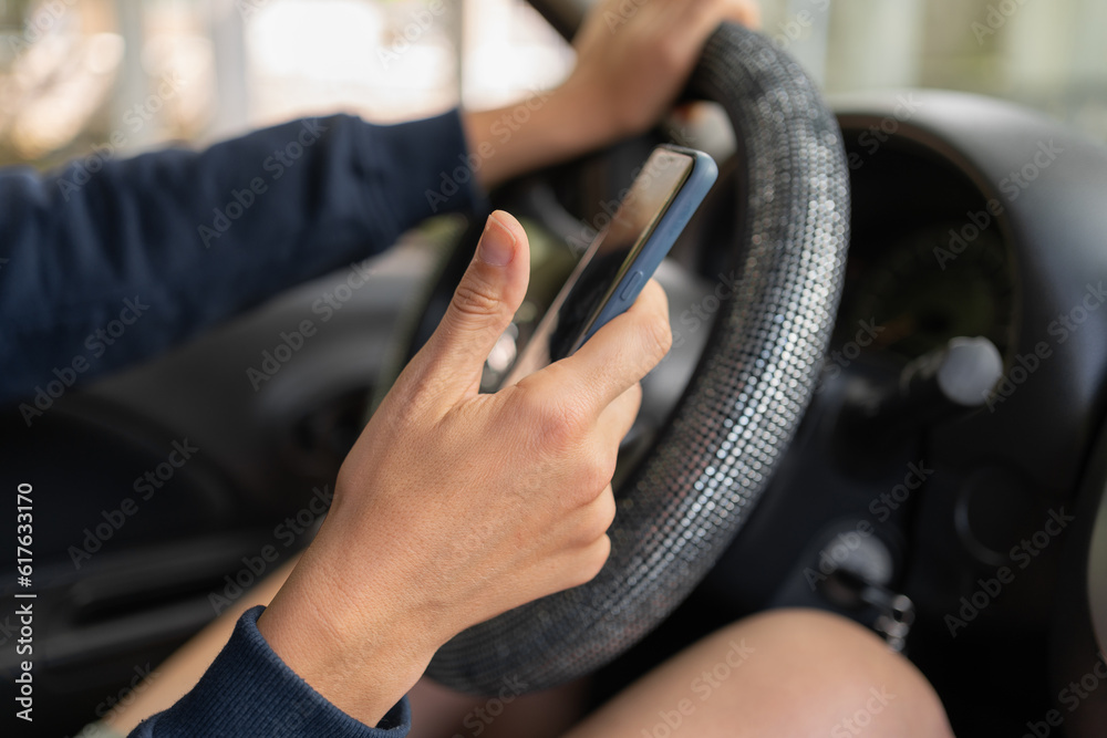 Woman drive a car and use smartphone, reading messages holding a cellphone while driving. Dangerous behavior, accident risk. Danger, transgression, youth concept.