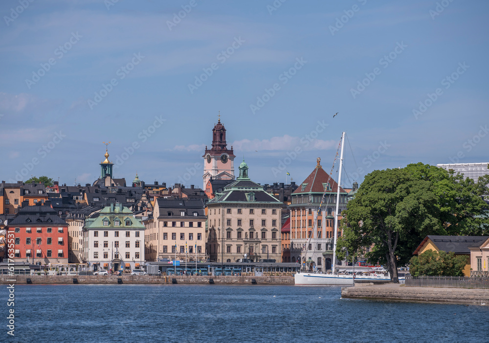 The old town Gamla Stan apartment and churches, pier with boats, a sunny summer morning in Stockholm