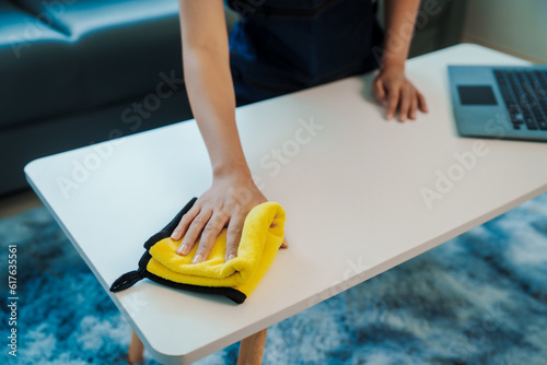 Cleans floor and desk. Hand of asian chinese woman wiping work desk, close-up.