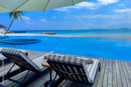 Fototapeta Naklejka Na Ścianę i Meble -  Chairs  as Umbrella In Palm Beach near poolside in the tropical blue background