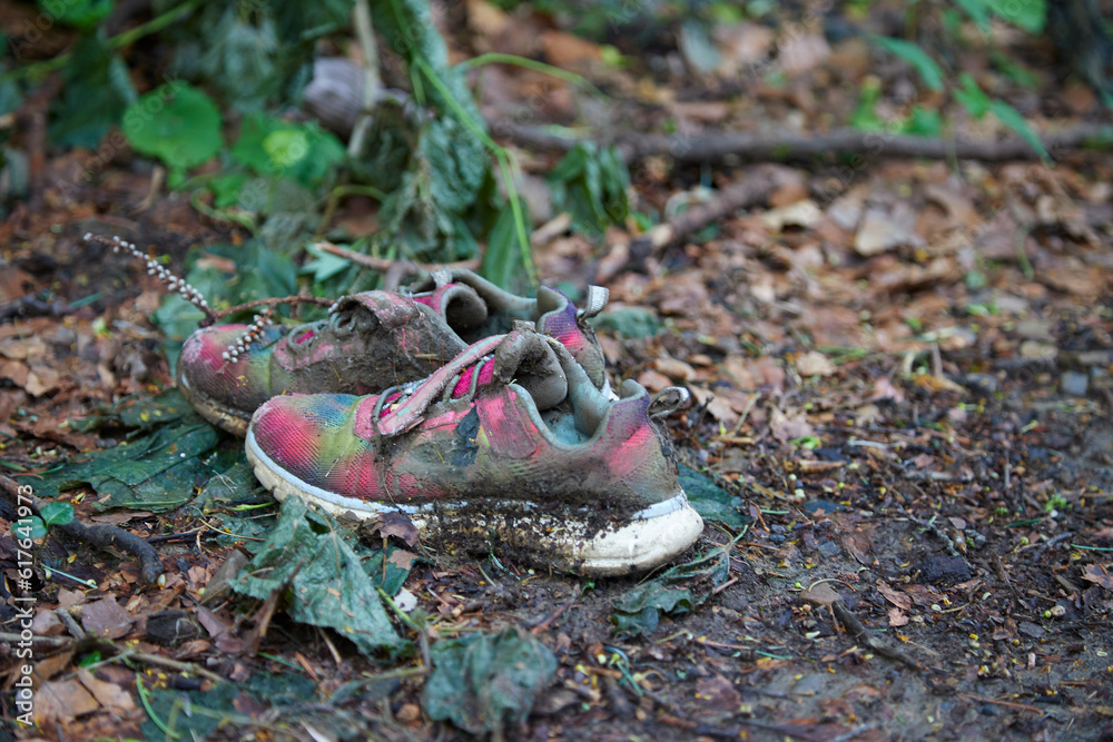 dirty sport shoes on the ground in a forest