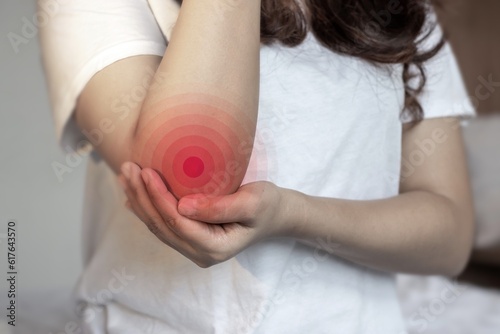 Pain in the elbow joint of Asian young woman. photo