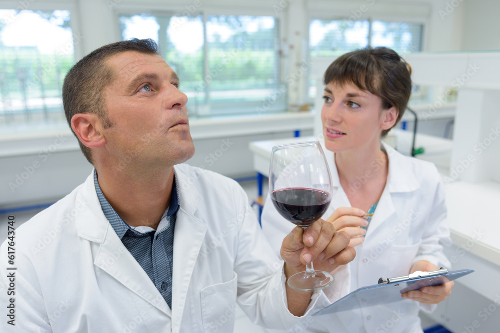 two researchers in white coat checking wine acidity in laboratory two researchers in white coat checking wine acidity in laboratory