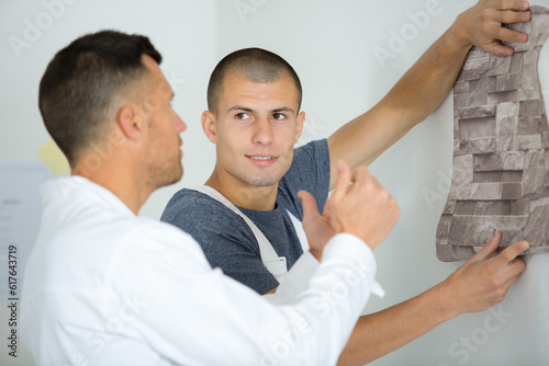 decorator holding roll of wallpaper against the wall