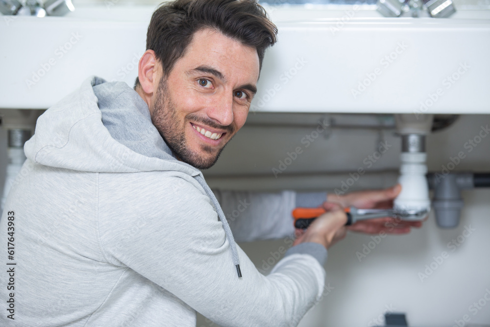 casually dressed man repairing sink waste pipe casually dressed man repairing sink waste pipe