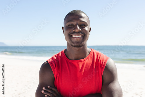 Portrait of happy african american man looking at camera and smiling on sunny beach