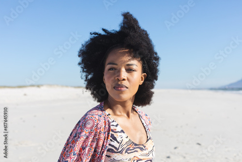 Thoughtful african american woman sitting on sunny beach looking away